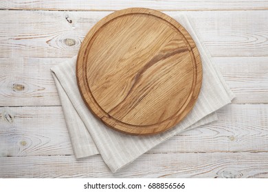 Pizza board and canvas napkin with lace on wooden table. Top view mock up