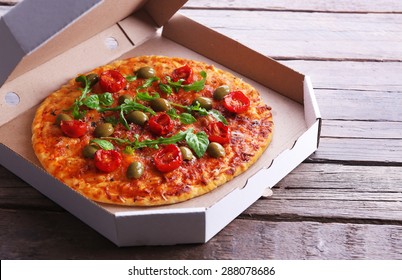 Pizza in box on wooden table, closeup