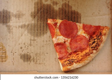 Pizza Box With Single Slice Of Old Pepperoni Pizza In Delivery Box Left After The Party. Cold Pizza Leftovers In Greasy Cardboard, Top View From Above