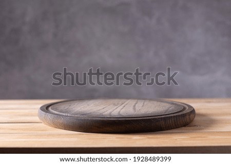 Pizza or bread cutting board for homemade baking on wooden table near grey wall. Food recipe concept at wood background texture with copy space. Front view
