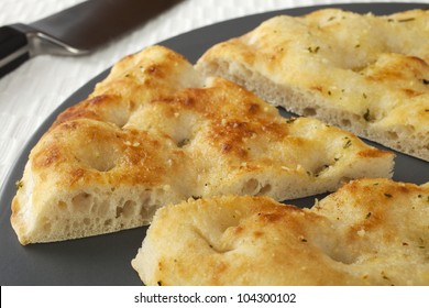 Pizza Bread With Garlic And Herbs, On A Platter With One Slice Cut.