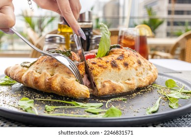 Pizza calzone with basil leaves close up with restaurant background. classic italian food
