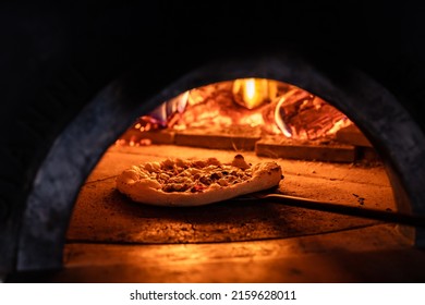 Pizza concept. Preparing traditional italian pizza. Long shovel for pizza, baking dough in a professional oven with open fire in interior of modern restaurant kitchen - Powered by Shutterstock