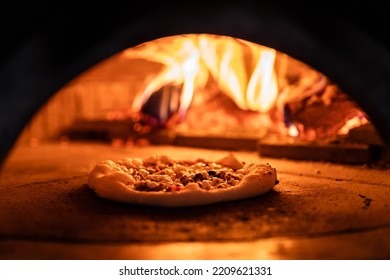 Pizza concept. Preparing traditional italian pizza. Long shovel for pizza, baking dough in a professional oven with open fire in interior of modern restaurant kitchen - Powered by Shutterstock