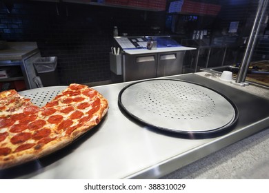 A Pizza Counter With One Pizza And An Empty Pizza Round.