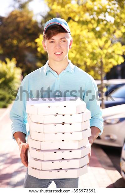 Pizza\
delivery boy holding boxes with pizza,\
outdoors