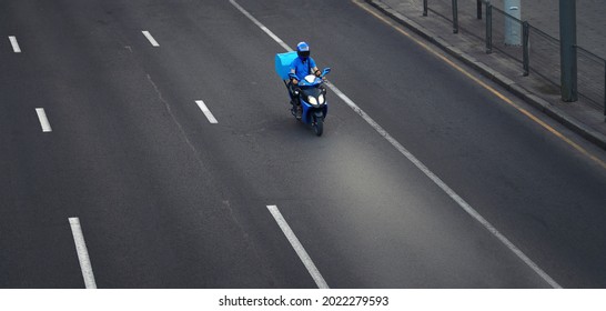 Pizza Delivery Boy Riding Motor Bike On The City Street In Evening, Take Out Food. Delivery Man Of Takeaway Food Service On Scooter With Trunk Case Box Driving Fast. Courier Delivering Food By Scooter