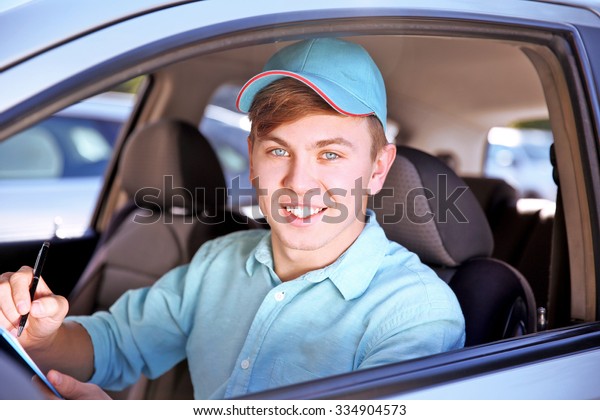 Pizza delivery\
boy with tablet in car,\
close-up