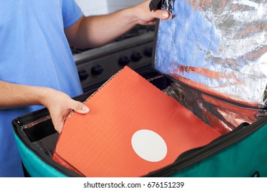 Pizza Delivery Person Putting Food Into Insulated Bag In Restaurant Kitchen