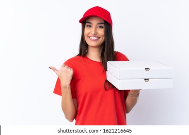 Pizza Delivery Woman Holding A Pizza Over Isolated White Wall Pointing To The Side To Present A Product