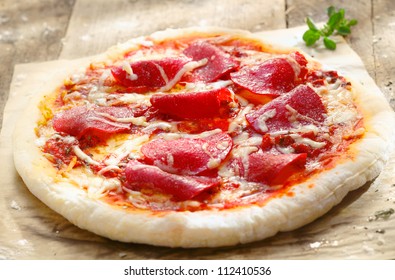 Pizza Diavolo With Salami Meat And Red Hot Chili Peppers On A Rustic Table In A Pizza Parlor, For Italian Cuisine Concept