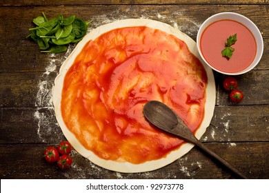 Pizza Dough With Tomato Sauce On Rustic Wooden Table