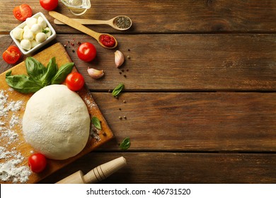 Pizza dough with tomatoes, olive oil, green basil and Mozzarella on wooden background - Powered by Shutterstock