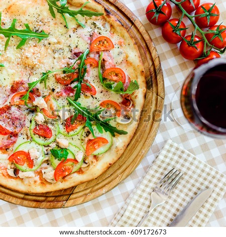 Pizza with glass of wine and sprig of tomatoes