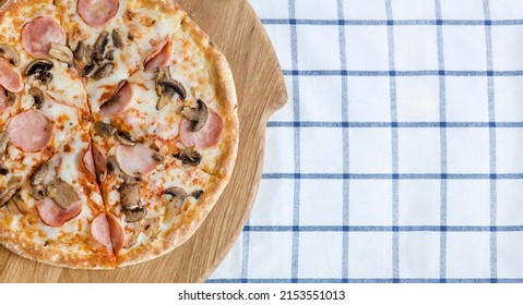 Pizza With Ham And Mushrooms On A Wooden Board And Blue Napkin, Top View. Food Photo For Pizzeria, Menu, Catalog, Banner, Leaflet,