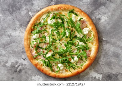 Pizza with ham slices under browned melted mozzarella garnished with piquant cream cheese mixed with spicy Italian herbs and fresh green arugula on gray stone surface - Shutterstock ID 2212712427