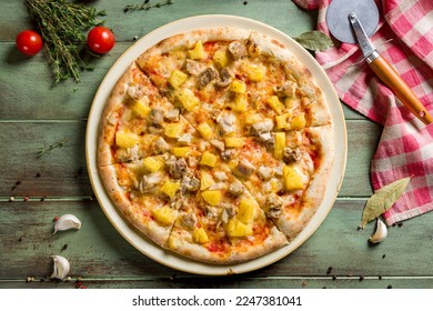 pizza Hawaiian with pineapple and chicken top view on green wooden table