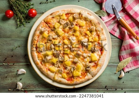 pizza Hawaiian with pineapple and chicken top view on green wooden table