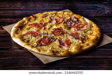 Pizza with hum, sesame and tomato on a wooden table
