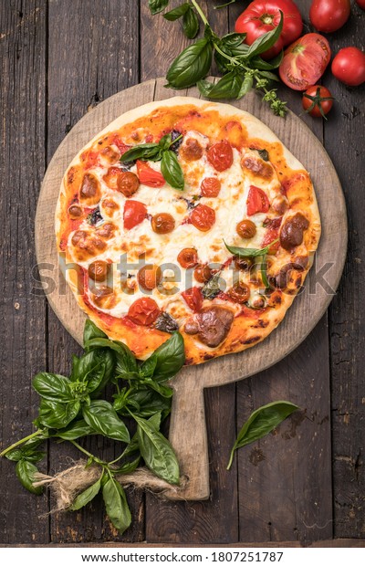 Pizza Margarita cut in\
slices on a wooden background. Fast food. Unhealthy food. Tasty\
pizza.