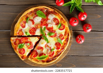 Pizza Margherita on cutting board, fresh tomatoes and basil. Top view, flat lay - Powered by Shutterstock