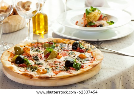 Pizza with Mozzarella Cheese, Fresh Tomato and Pesto Sauce. Served at Restaurant Table