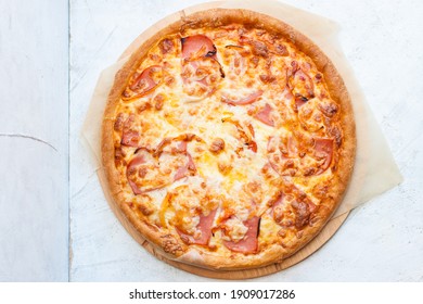 Pizza with mozzarella cheese, ham, tomatoes and sauce on plain grey background