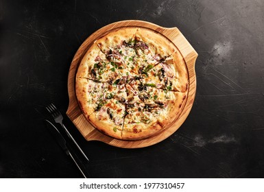 Pizza On A Wooden Base On A Black Textured Background Top View