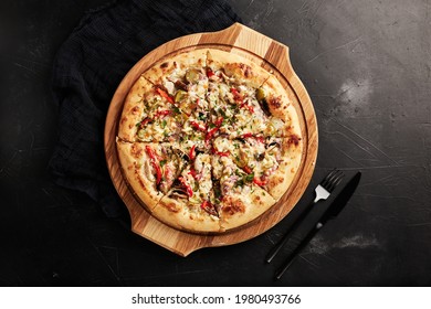 Pizza On A Wooden Base On A Black Textured Background Top View