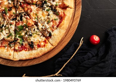 Pizza On A Wooden Base On A Black Textured Background Top View