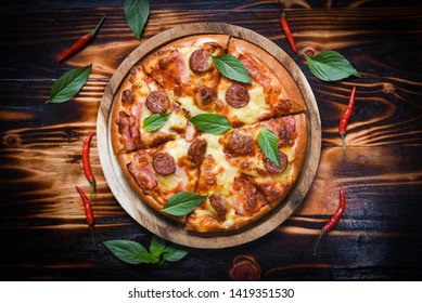 Pizza on wooden tray and chilli basil leaf top view / delicious tasty fast food italian traditional pizza cheese with Mozzarella , Smoked pork sausage , Pineapple ham on topping sauce  - Powered by Shutterstock