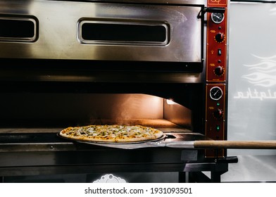 A pizza in a oven burning. Pizza is taken straight from the oven