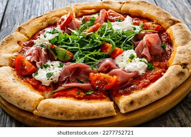 Pizza parma - prosciutto di parma, arugula, mozzarella, tomatoes, burrata on wooden table