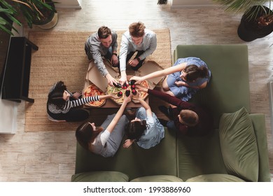 A Pizza Party, A Group Of Friends Chatting And Happily Eating Pizza At The Table And Drinking Sweet Soda Water. Top View From The Second Floor. High Quality Photo