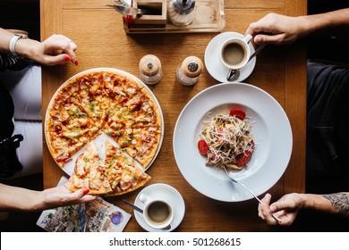 Pizza And Pasta On A Table With Hands