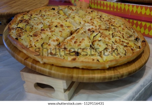 Pizza pie large tray is divided into small\
triangular pieces.