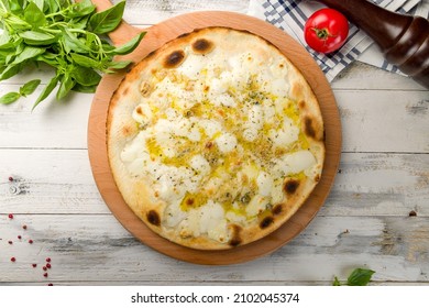 Pizza Quattro formaggi with four tips of cheese on wooden table top view on white wooden table