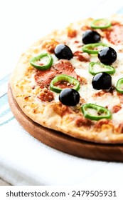 Pizza with salami, jalapeno pepper and black olives. Home made food. Concept for a tasty and hearty meal. Close up.
