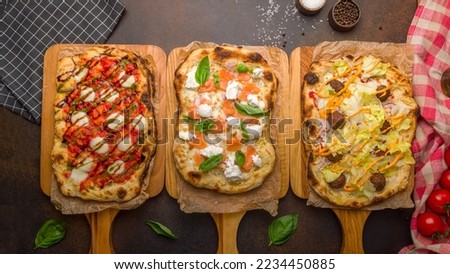 Pizza with salmon and cheese, Pinsa margarita buffalo, pinsa with falafel, vegetables salad ,Roman dough, pinsa top view on dark brown table