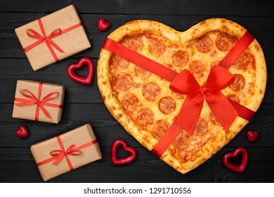 Pizza Shaped Heart With Red Bow Ribbon And Present Box For Valentine's Day Romantic Concept On Rustic Dark Black Background. Top View. Flat Lay.