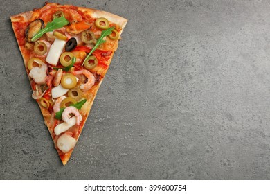 Pizza slice with seafood, red pepper and olives on grey background