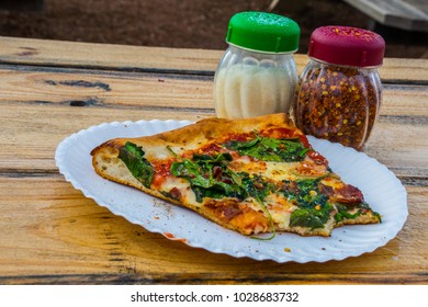 Pizza Time , A Slice Of Pizza With Spinach And Bacon And Goat Cheese With Herbs And Parmesan Cheese Sitting On A Wooden Table. Ready To Eat With Parmesan Shaker And Hot Peppers