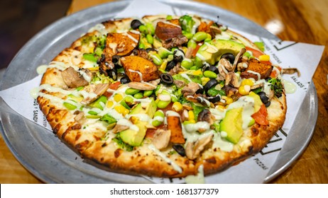 Pizza topped with black olives, mushrooms, golden corn, broccoli, avocado, edamame, and sweet potatoes - Powered by Shutterstock