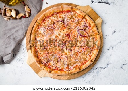 Pizza with tuna and red onion on the board on grey table top view