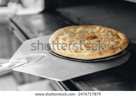 Pizzamaker worker puts pizza into an electric oven, business pizzeria concept.