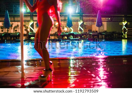 PJ or go-go dance in the rain on a wooden dance floor under an umbrella near the pool. Abstract blurred image