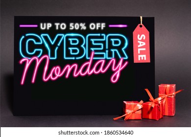 placard with up to 50 percent off, cyber monday lettering and sale tag near presents on dark background