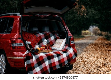 A place with a blanket and mulled wine for a picnic in the trunk of a red car - Powered by Shutterstock