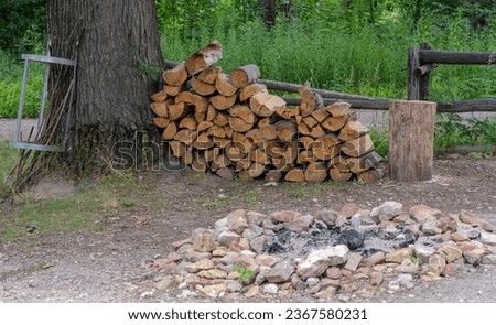 A place to camp on a forest tourist trail. Chopped wood and a fenced fireplace.Camping place for tourists. There is a visible supply of wood, a log for chopping wood, a place for a bonfire fenced.