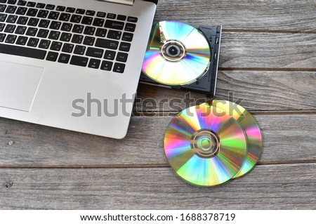 
Place the CD or DVD ROM in the laptop computer and blank DVD on the gray wooden floor.